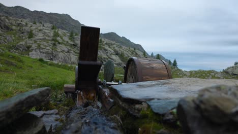 una rueda de agua de madera tradicional y un arroyo de montaña en movimiento