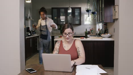 a man serving his wife wine while she works