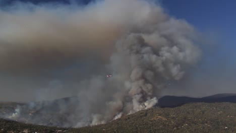 footage of plane flying through smoke plume of california wildfire spreading across mountains