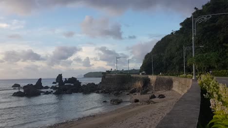 Mountain-side-road-by-the-ocean-and-giant-corals-and-thick-clouds-in-Batanes,-Philippines