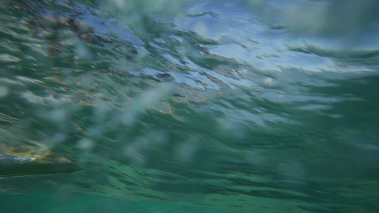 Surfer riding on a wave in crystal clear water in Byron Bay Australia shot from underwater in slow motion