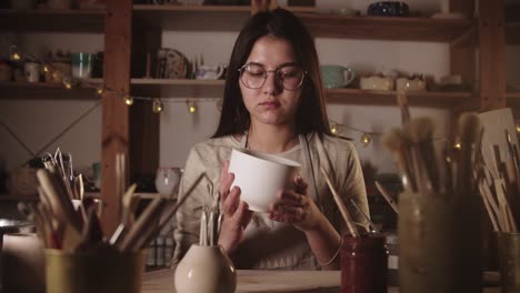 joven alfarera sosteniendo una gran taza de té de cerámica blanca