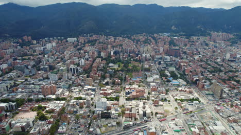 Vista-Aérea-De-Drones-De-Una-Gran-Ciudad-Latinoamericana-Urbana-Frente-A-Una-Gran-Montaña-Durante-El-Día-Nublado