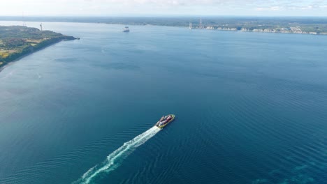 vista aérea de un ferry que cruza el canal de chacao con la construcción de un puente entre el continente y la isla grande de chiloé en el fondo