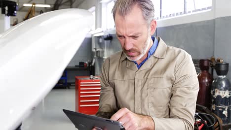 Mechanic-using-digital-tablet-while-servicing-a-car-engine