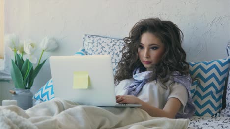 mujer trabajando en la computadora portátil en la cama