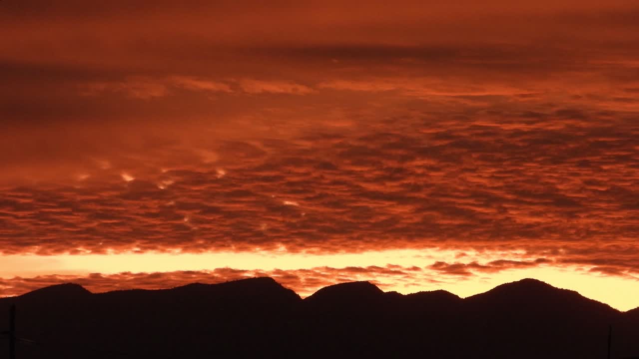 "Mesmerizing time-lapse sunrise over majestic mountains, featuring vibrant red skies, shifting clouds, and the gradual ascent of the sun