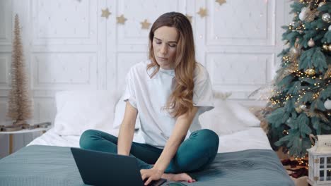 Mujer-Concentrada-Sentada-Con-Un-Cuaderno-En-Un-Sofá-En-Una-Casa-Decorada-De-Año-Nuevo.