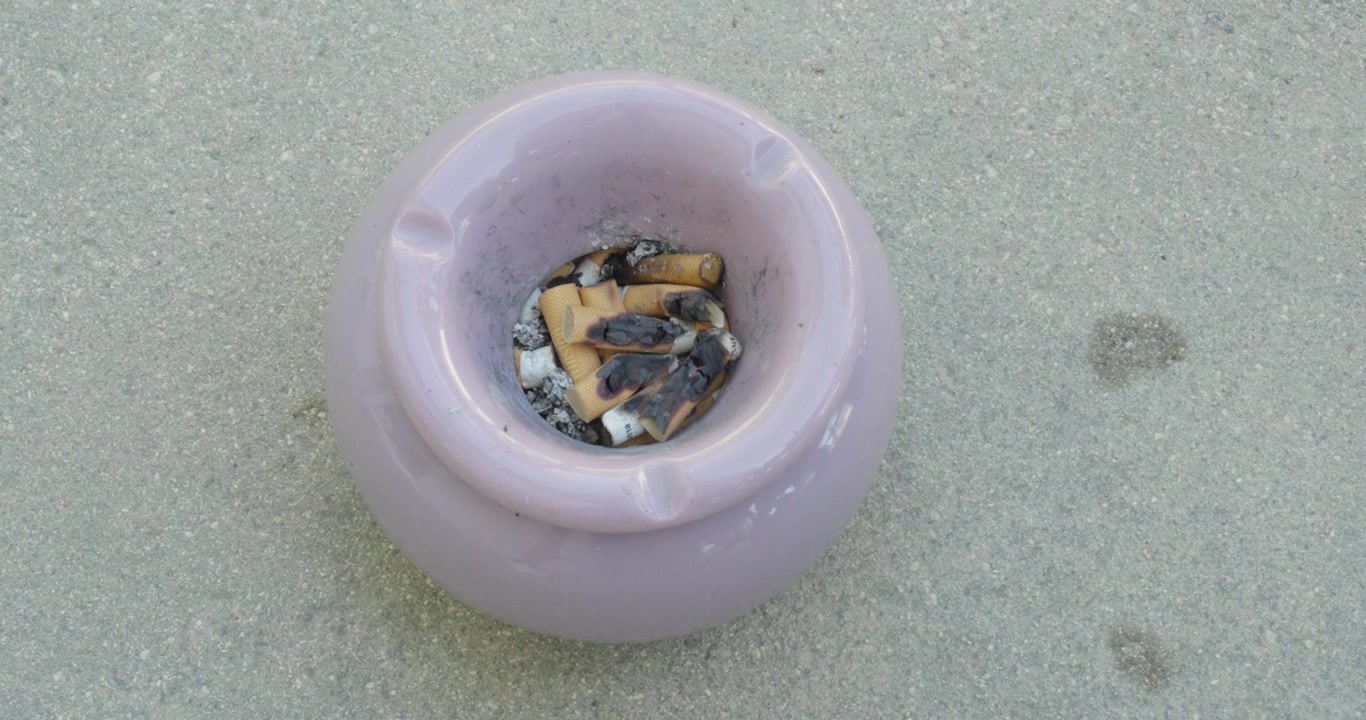 Close-up of an ashtray filled with smoked cigarette butts and ash, illustrating heavy smoking, tobacco waste, nicotine addiction, and smoking-related health concepts.