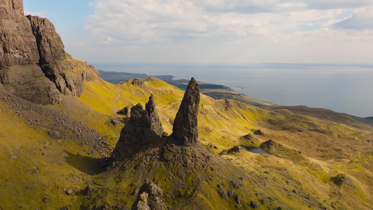 Aerial drone footage of the dramatic mountain landscapes and Old man of Storr on the Isle of Skye, Scotland. Sweeping panoramic views of majestic peaks, green valleys, and wild nature