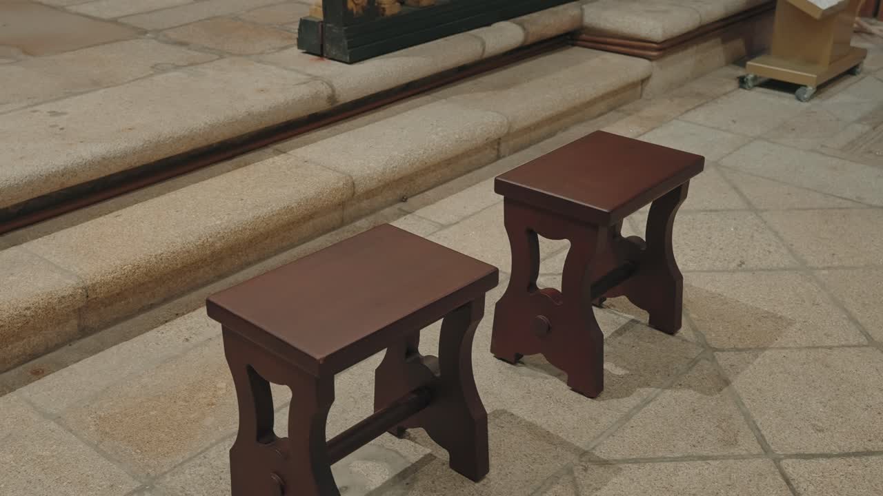 Two wooden prayer stools arranged near stone steps inside church