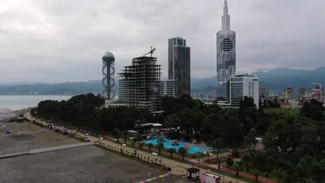 Drone-aerial-view-in-Georgia-flying-over-Batumi-city-and-beach-next-to-the-Black-sea-showing-skycreapers-and-buildings-on-a-cloudy-day