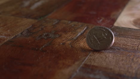 quarter dollar coin spins on the wooden floor