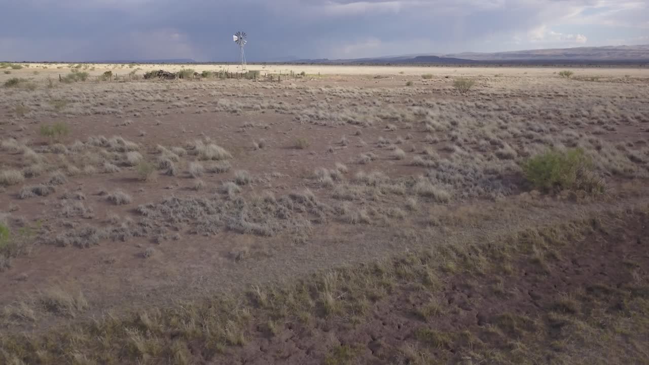 drone moviéndose lentamente a través del paisaje con molino de viento y cielos en el fondo, texas