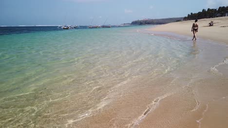 walking around beautiful nusa dua beach in bali indonesia. waves splashing on the beach and ocean in background with amazing yellow sand. exotic nature peoples enjoy the most