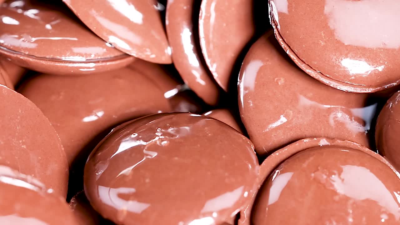 A detailed look at shiny, smooth chocolate discs stacked closely together, highlighting their glossy texture.