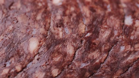 black bull sausage ham, tongue pork dry-cured sausage on a black background, traditional spanish delicatessen food, close up.