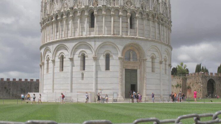 Carrellata verso l'alto da un cartello "Non calpestare l'erba" per rivelare la famosa destinazione turistica del Battistero di Pisa in Italia
