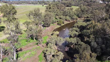 Aerial-View-Of-Double-Kayak-Paddling-Down-River-And-Passing-Winery