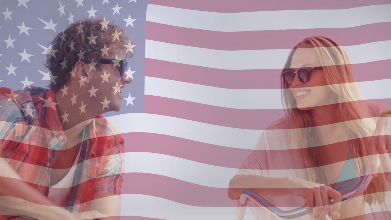 animación de la bandera estadounidense sobre una pareja sonriente montando bicicletas