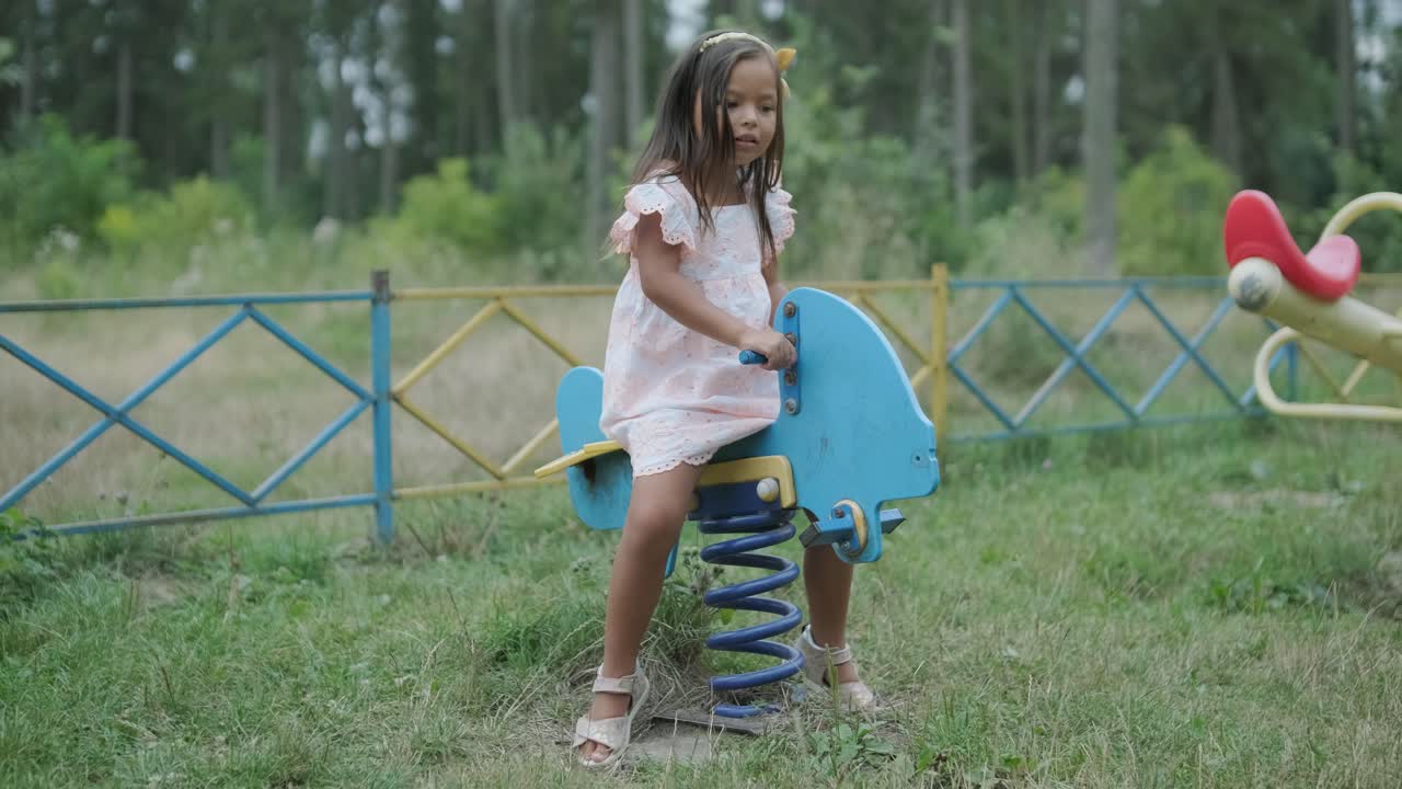 una madre embarazada y su hija joven disfrutan de un tiempo de juego juntos en un patio de recreo en el parque, rodeados de árboles y vegetación