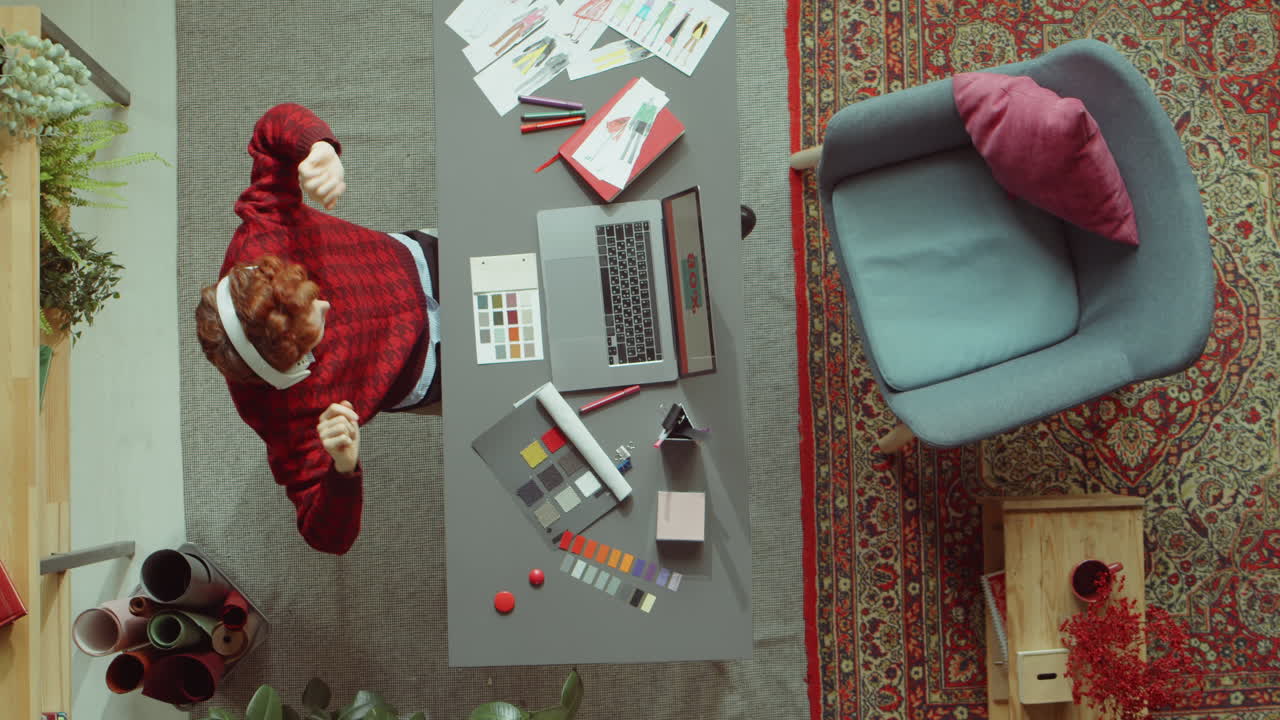 женщина-дизайнер слушает музыку с наушниками на рабочем месте