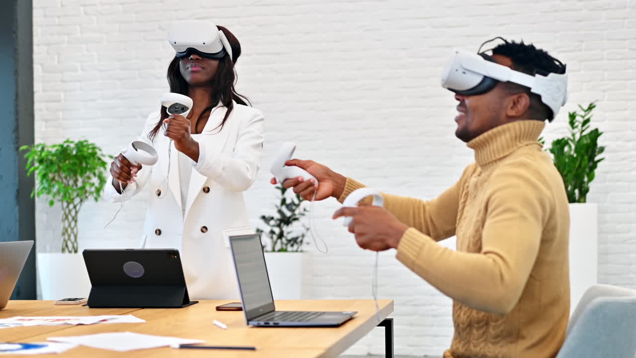 Business conference in VR in an office. A black man and woman using VR glasses and controllers, gadgets on the table. Slow motion