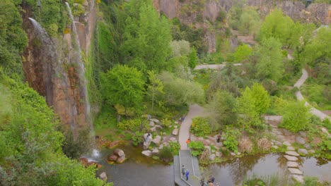 Jardin-extraordinaire-in-nantes-with-lush-greenery,-pathways,-and-a-cascading-waterfall,-aerial-view