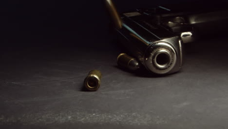 bullets drop near handgun on table and roll away, slow motion