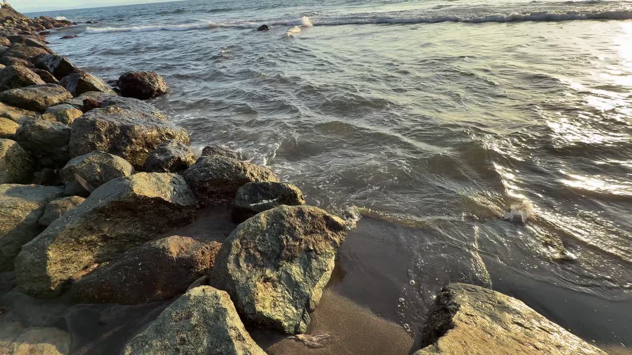 Ondas do mar lavando suavemente rochas e praia arenosa