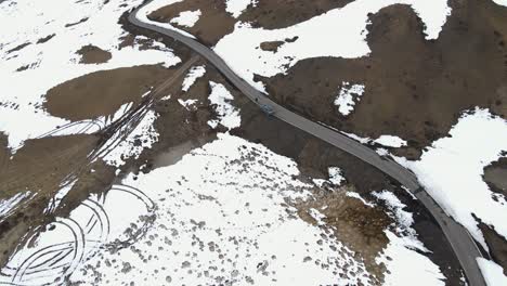 Vista-Aérea-De-La-Carretera-Nevada-De-Las-Altas-Montañas-De-Hielo-Con-Conducción-De-Automóviles-En-El-Pueblo-Más-Alto-Del-Mundo,-Hikkim,-En-El-Valle-De-Spiti,-En-Himachal-Pradesh