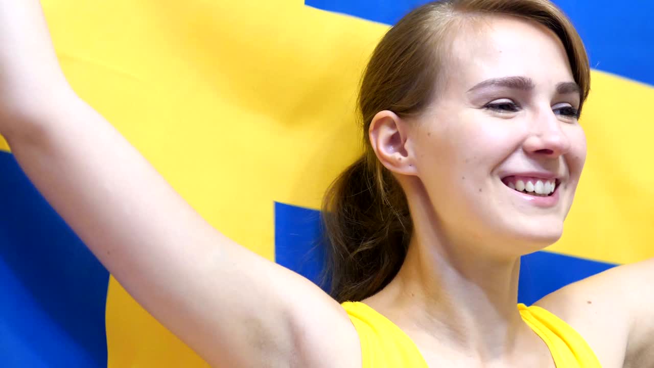 스웨덴의 젊은 여성이 슬로모션으로 스웨덴의 발을 들고 축하합니다.