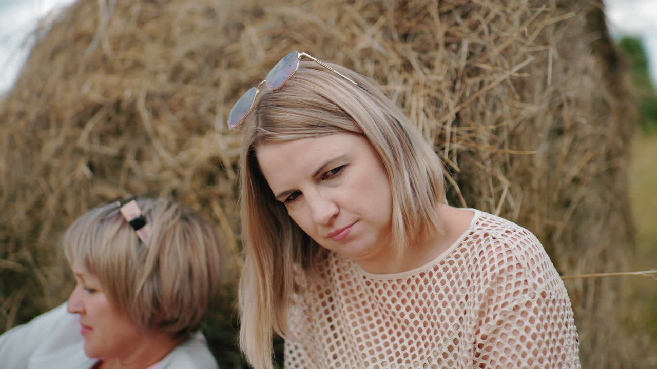 선글라스를 착용한 망 옷을 입은 여자가 반사하는 순간을 경험하고, 멀리 쳐다보면서 머리를 약간 기울이며, 거대한 개방된 에서 앞을 바라보는 다른 여자를 동반합니다.