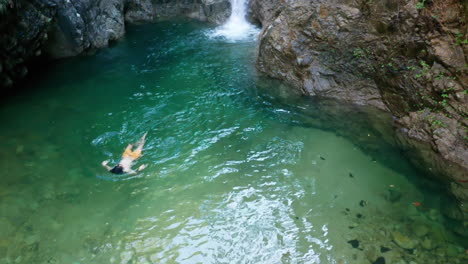 hombre nadando en una piscina natural aislada con cascada en méxico, antena