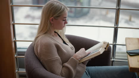 elegant lady seated, flipping to a new page in her book while deeply focused and thoughtful, soft light from the window creates a calm atmosphere, enhancing the quiet, reflective moment