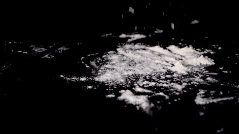 a person sprinkling the flour over table for making a dough, isolated on black background