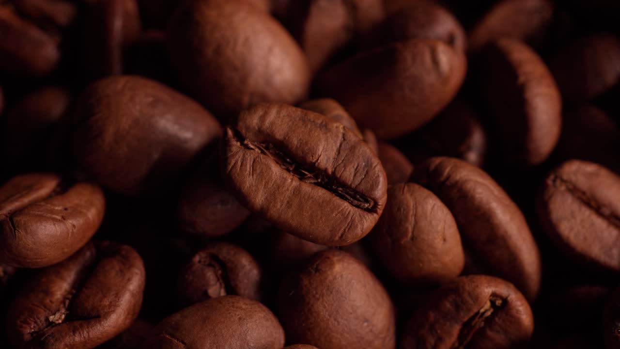 Makro-nærbillede af brune Arabica-kaffebønner, der afslører lys fra mørke til fokus.