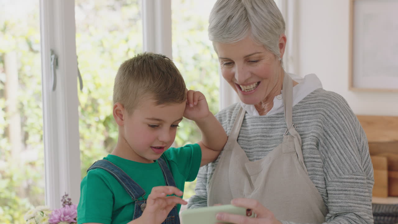 할머니와 아이가 스마트폰을 사용하여 비디오 채팅을 하고 있습니다. 작은 소년은 할머니와 함께 휴가 주말을 나누고 손자와 함께 집에서 휴대 전화로 채팅을 즐기고 있습니다.