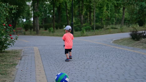small male kid runs by the paved alley in the park. active toddler spending time outdoors in summer.