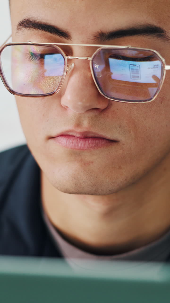 Giovane uomo con gli occhiali concentrato sullo schermo del computer