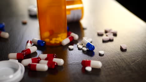 píldoras de medicamentos recetados, narcóticos, analgésicos y frascos de farmacia que caen sobre una mesa