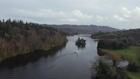 Scenic-landscape-aerial-ascending-above-fishing-boat-on-river-in-Spring