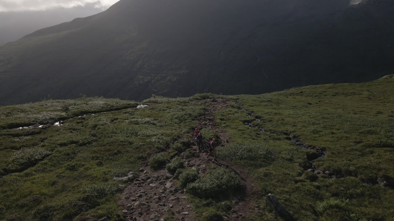Group Of Friends Hiking On A Mountainside - Hikers And Explorers Walking At Mountain - aerial drone shot