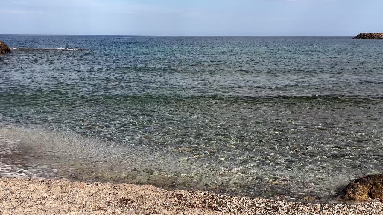 Tranquil shoreline with soft waves and clear water at Crete, Greece