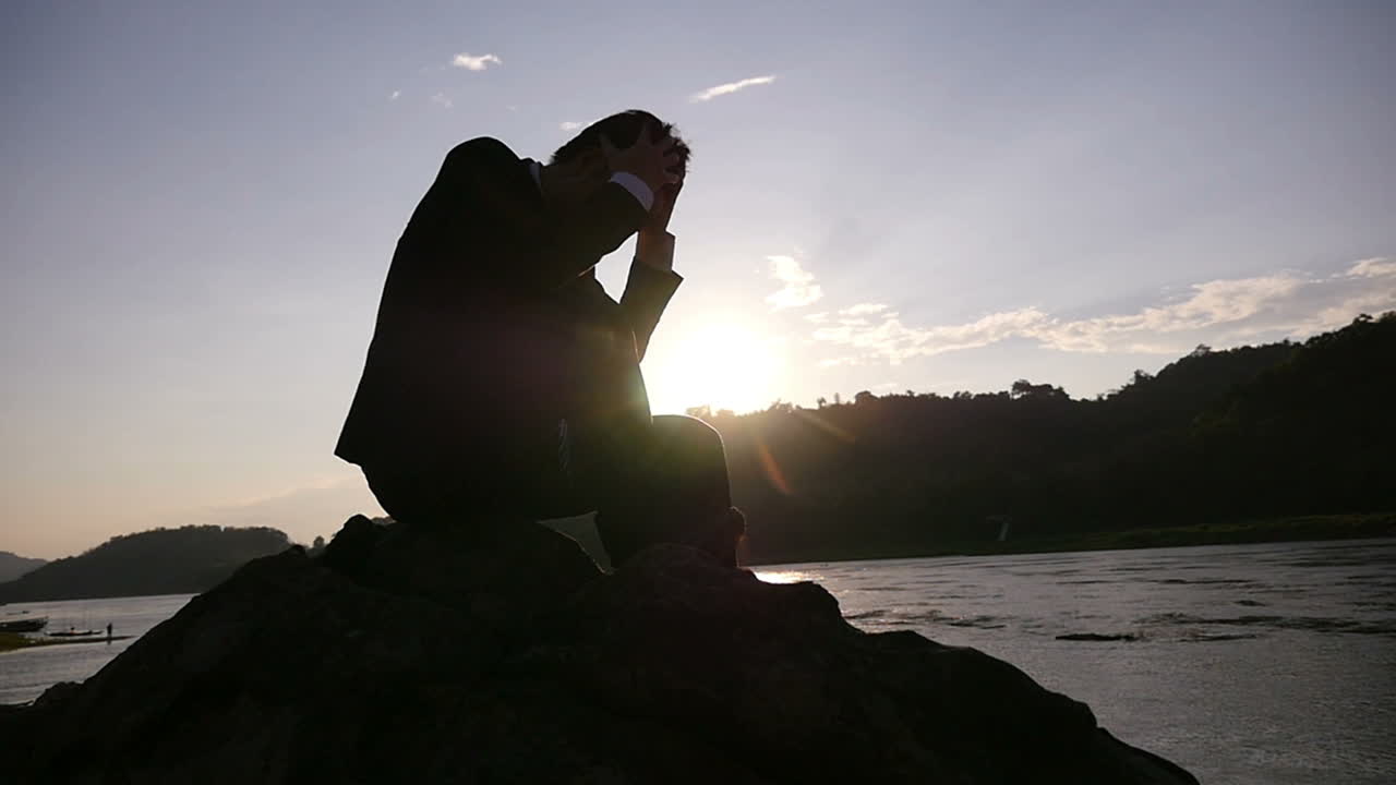 Man Sitting on a Rock at Sunset by a River