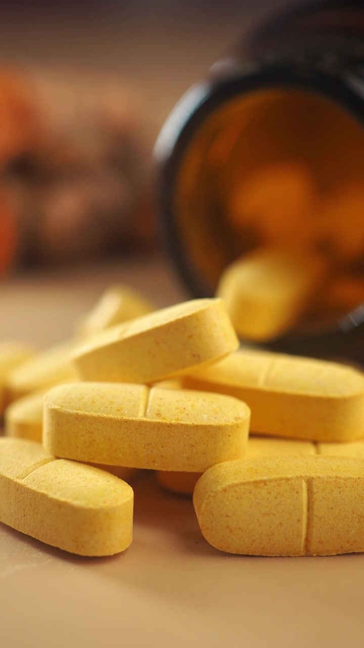 Pilules et comprimés jaunes renversés d'un flacon de médicaments.