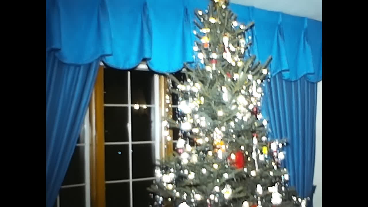 Christmas Tree in Living Room Next to Window. CIRCA USA - 1970s: A photo of a Christmas tree adorned with decorations stands in a 1970s living room, positioned next to a window.