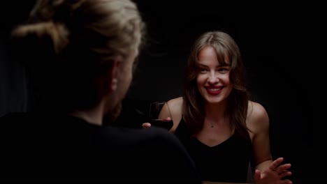 a beautiful woman is laughing at a man as she holds a glass of red wine - close up