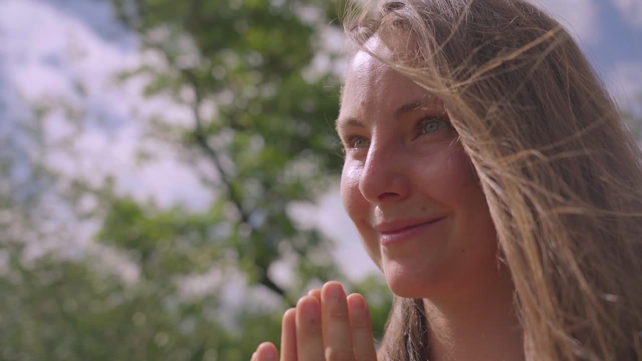 bella mujer sonriendo y haciendo yoga al aire libre en un día soleado, namaste manos