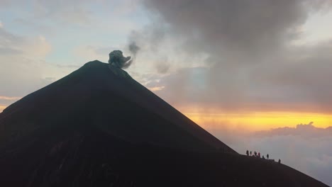 volcano erupting while a group of people is standing on a ridge close by